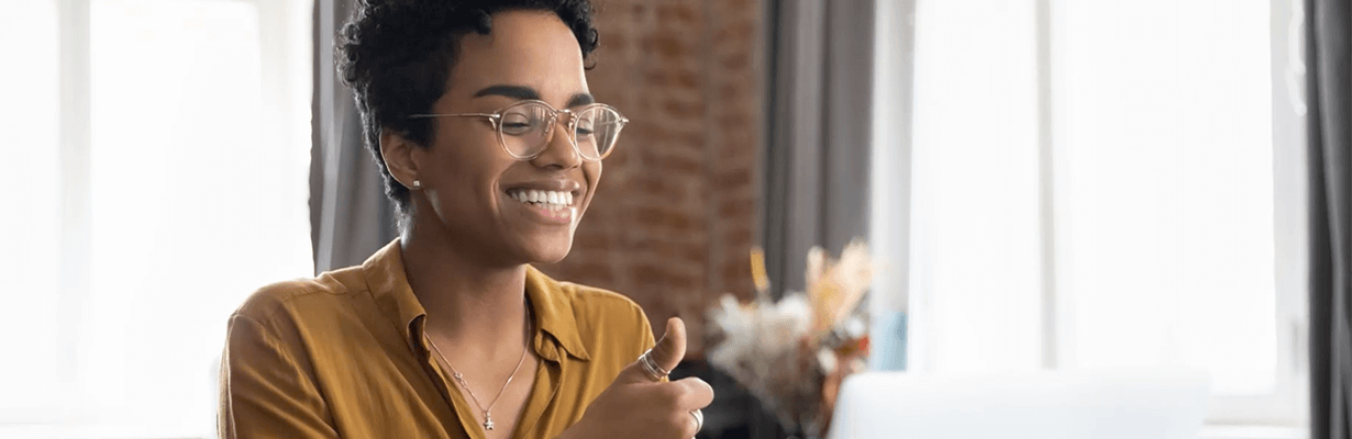 A female smiling and giving a thumbs up with her hand