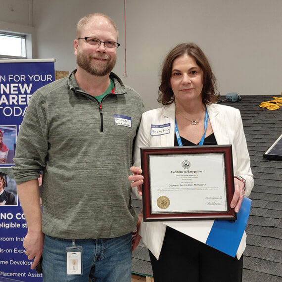 Two individuals standing next to each other holding an award