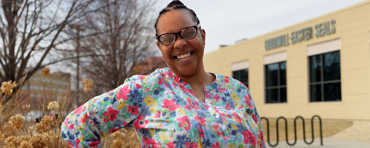 woman in floral shirt smiling and standing in front of Goodwill-Easter Seals Minnesota