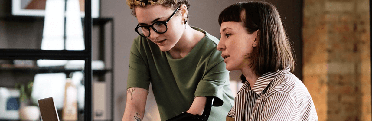 Two individuals working together in front of a laptop