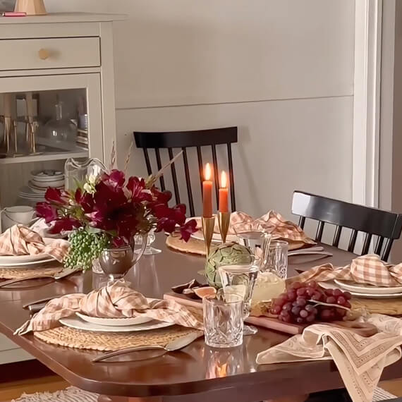 A dinning table with plate settings, candles lit and a charcuterie board a 