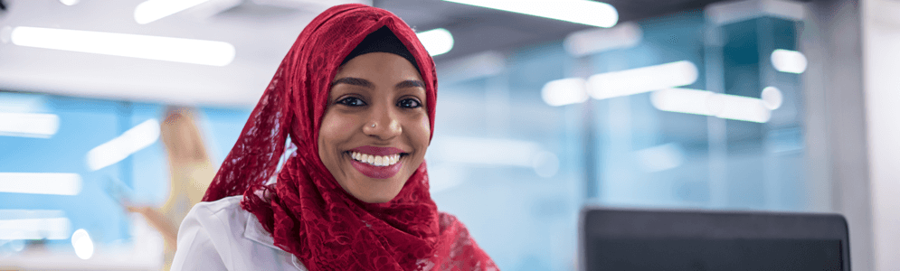 A muslim black female wearing a hijab while sitting in front of laptop