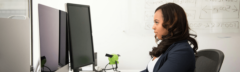 A female sitting in front of laptop and monitor, typing