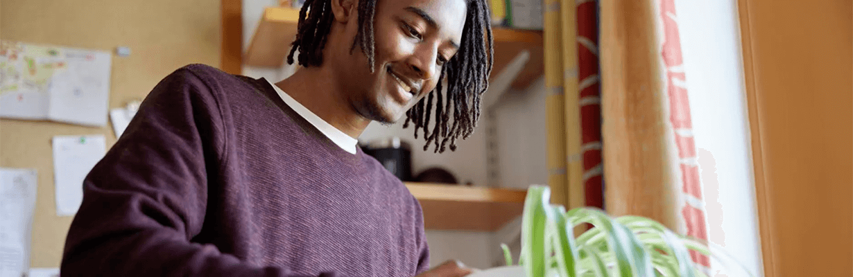 A male unboxing a plant from a moving cardboard box