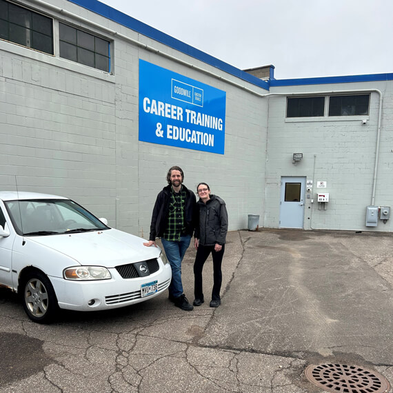 man and female standing next to a white 2006 Nissan Sentra car outside