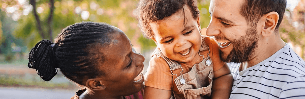 Two parents holding their child in their arms together