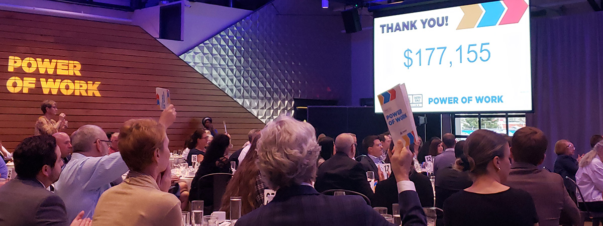 Photo of the Power of Work fundraising event live auction with tables filled with people in a ballroom