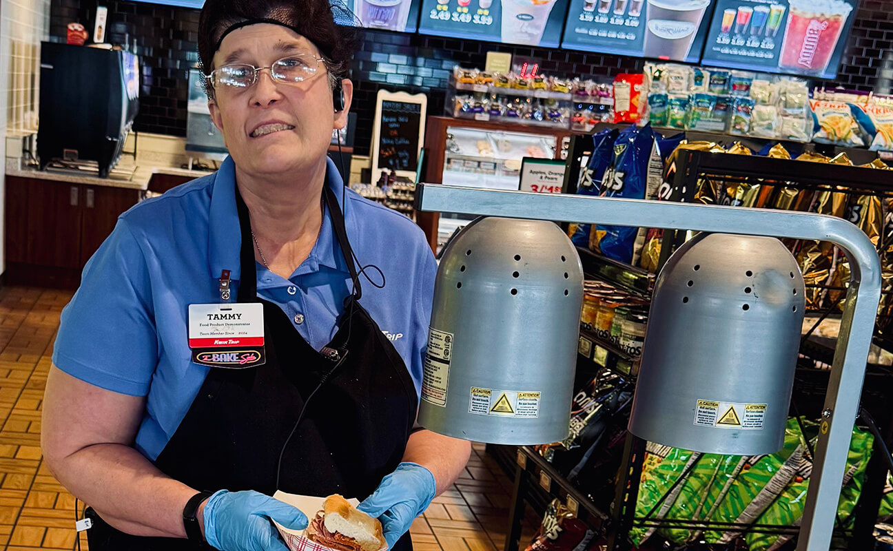 Tammy wears a Kwik Trip uniform and hair net while preparing food for the demonstration area