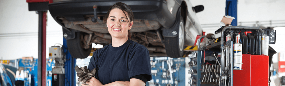 A female with her arms crossed, standing in front of a suspended car