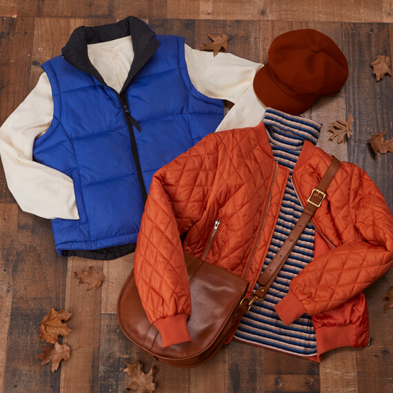 A jacket, hat, and bag rest on a wooden floor