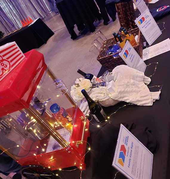 A table showing silent auction items at the Power of Work event including a popcorn machine