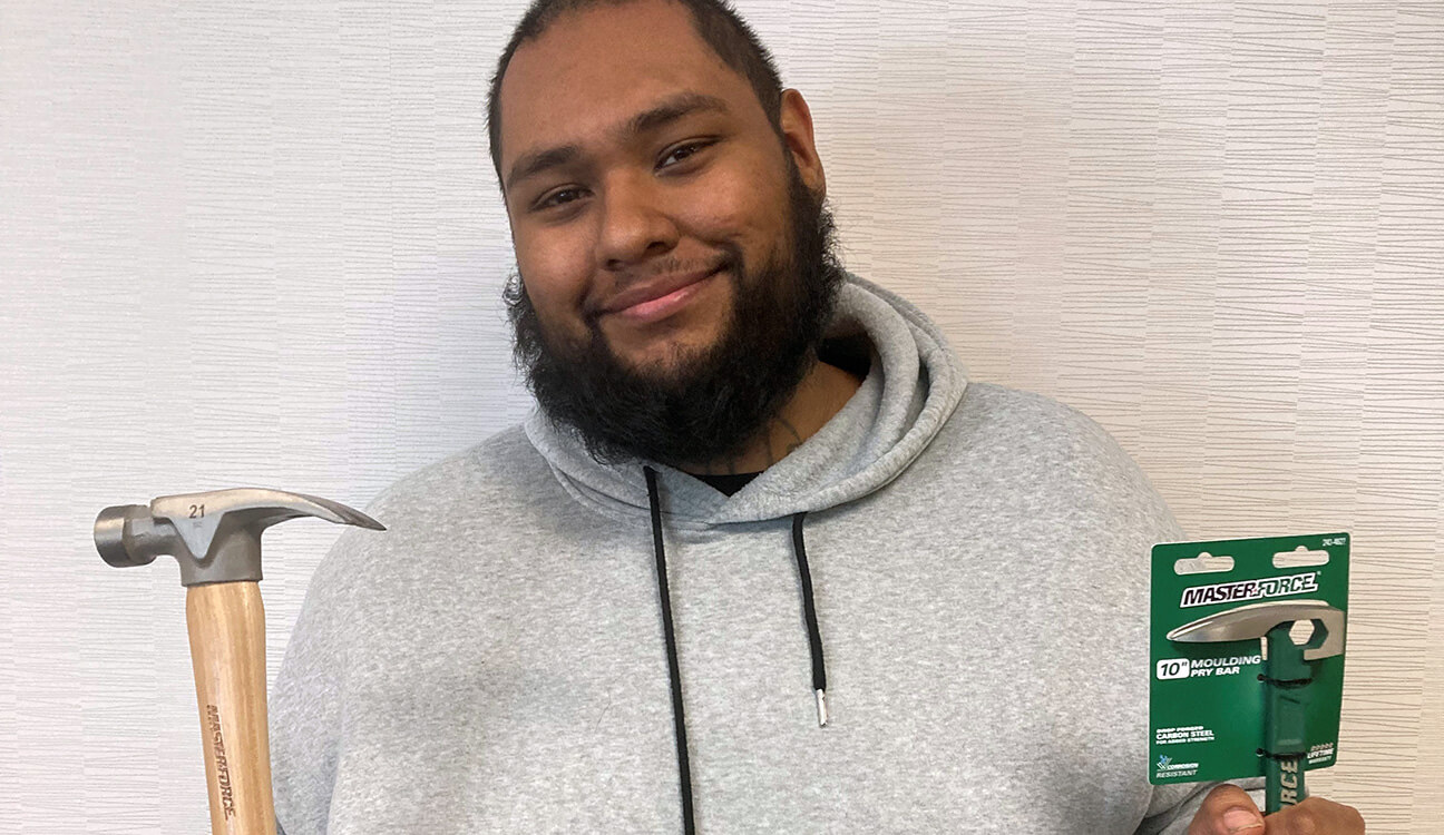 Pedro poses holding a hammer and tools that GESMN helped him secure for his new job