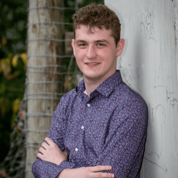 male wearing a dark purple floral button down shirt with a collar