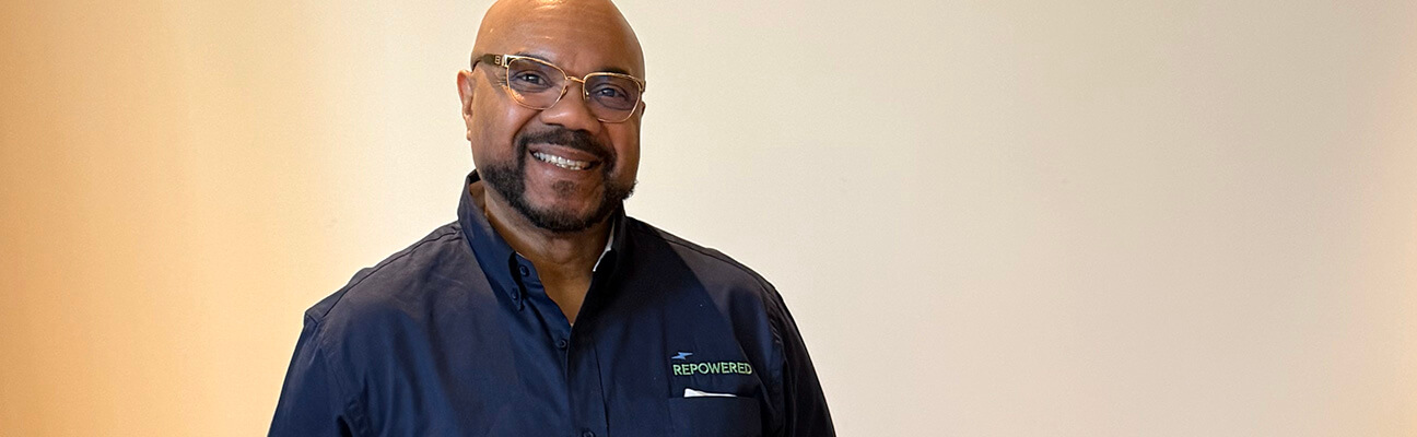 Glenn stands proudly working at a job fair for his employer